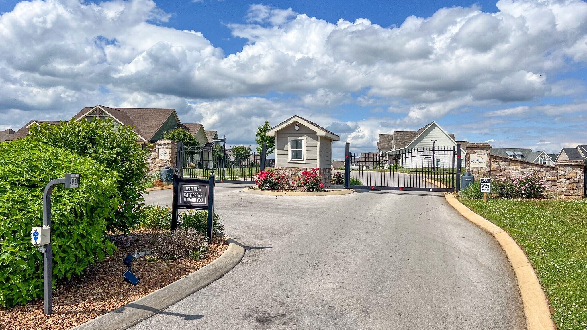 A gated entrance to a residential community with a clear sky and a sign indicating a 25 mph speed limit.