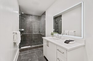 A modern bathroom with a glass-enclosed shower, white vanity, and a large mirror.