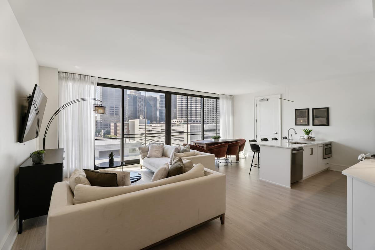 Un apartamento moderno con sala de estar, comedor y cocina, que cuenta con ventanas amplias y vista panorámica de la ciudad.