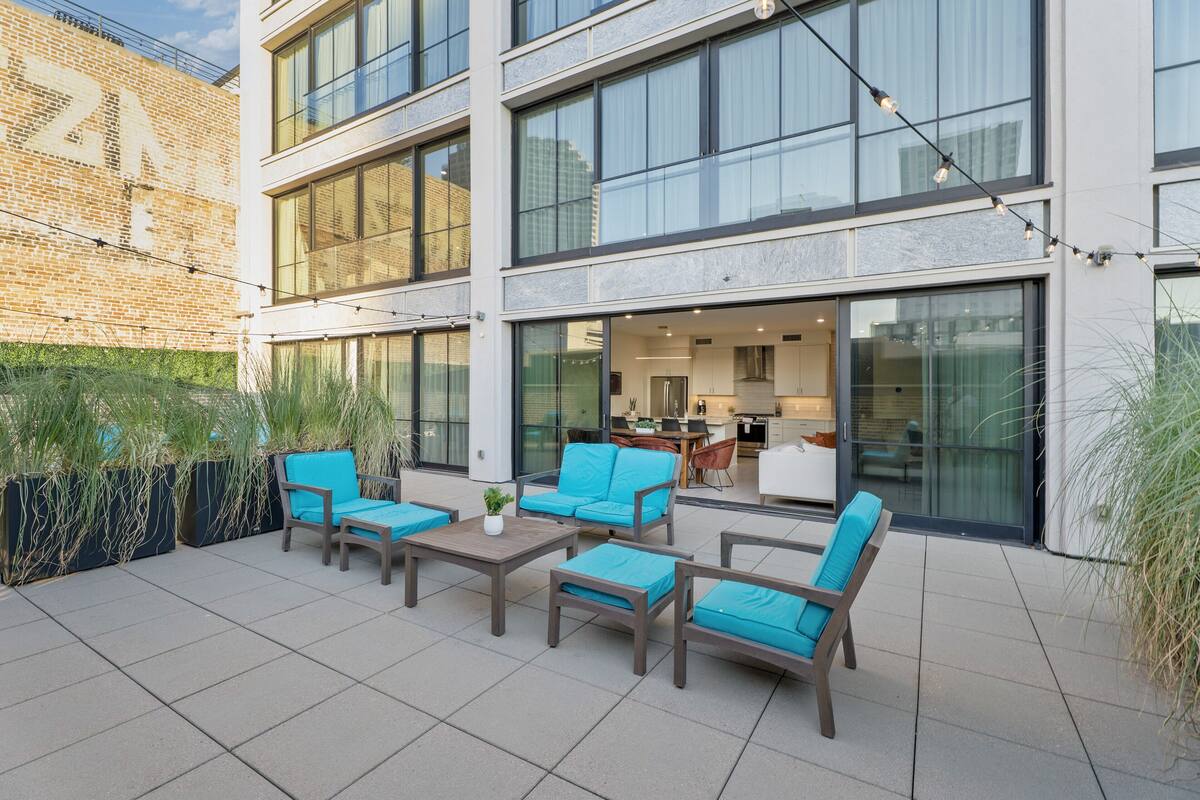 Un patio al aire libre con varias opciones de estar, incluyendo sofás y sillones, y una pequeña mesa.