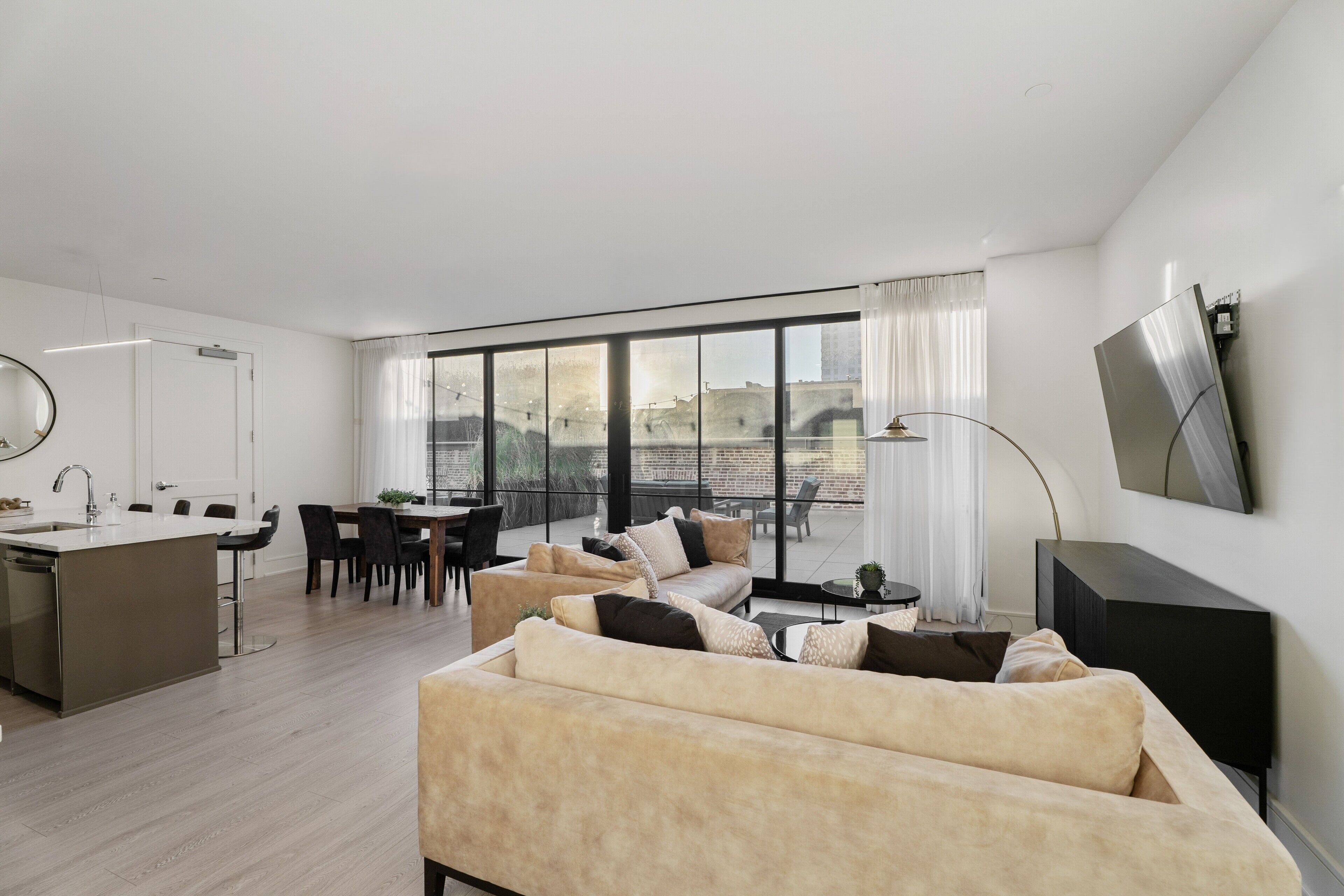 A modern living room with a sofa, dining area, and kitchen.