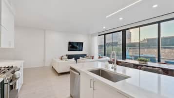 A modern kitchen with a large island, white cabinetry, and a built-in dishwasher.