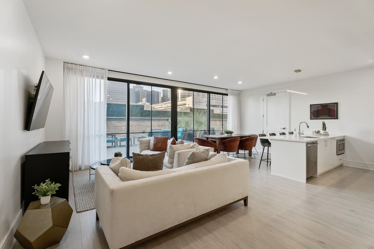 Un apartamento moderno con sala de estar, cocina y grandes ventanales con vistas a la ciudad.