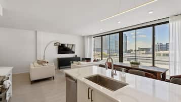 A modern kitchen with a large island, a dining area with a wooden table, and a sofa.