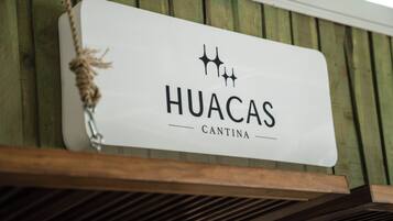 Un letrero con el texto 'HUACAS CANTINA' colgado de una estructura de madera.