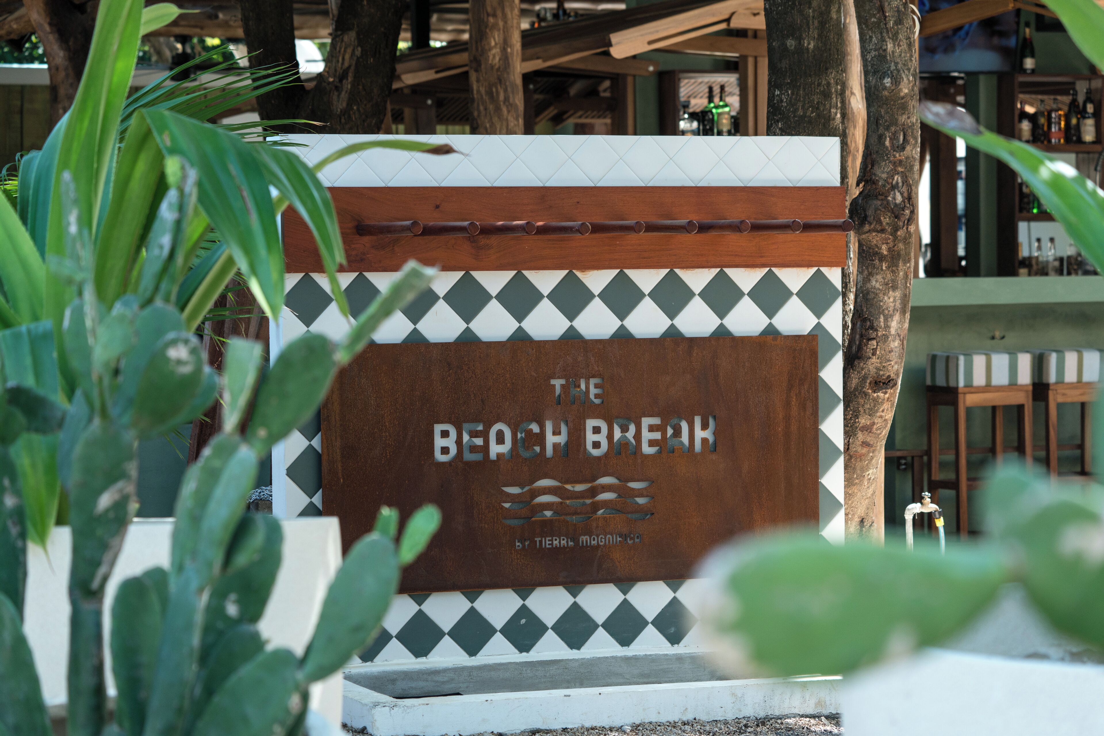 A sign for "The Beach Break" with a wave design and a logo.