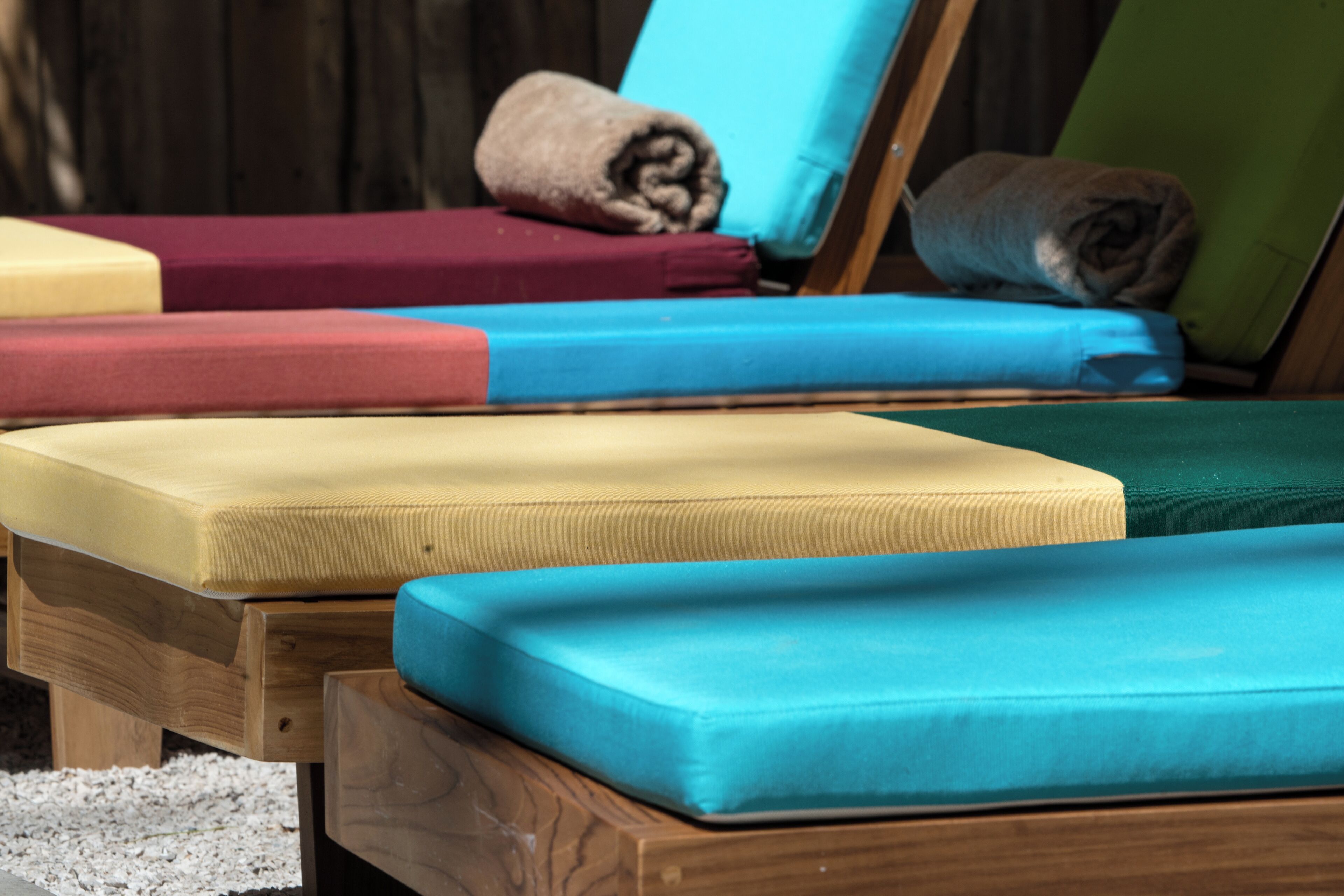 A wooden bed with multiple mattresses in various colors.