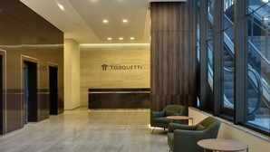 A modern lobby with a marble floor, a reception desk, and a staircase visible through large windows. - Palazzo Torquetti Condo Hotel e Eventos (Belo Horizonte)
