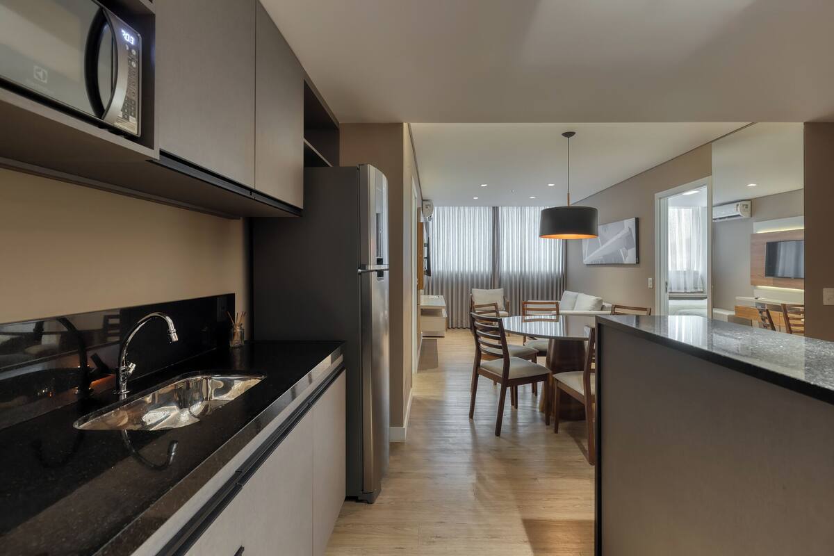 A modern kitchen with a built-in microwave, stainless steel sink, and a refrigerator.