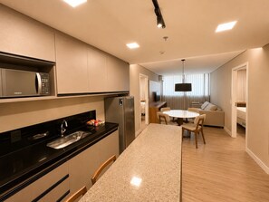 A modern kitchen with a built-in microwave, a refrigerator, and a dining area with a round table and chairs.