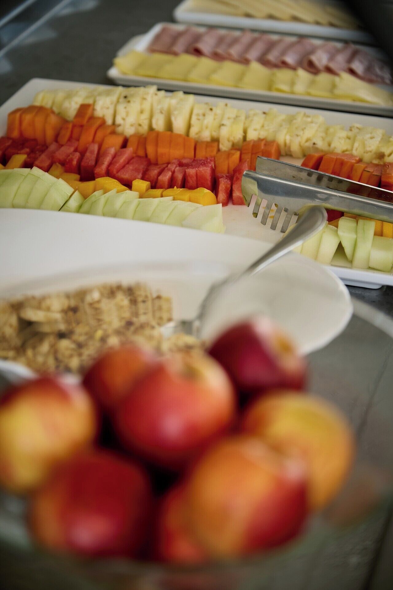 Un bufé con varias frutas y un bol de manzanas.