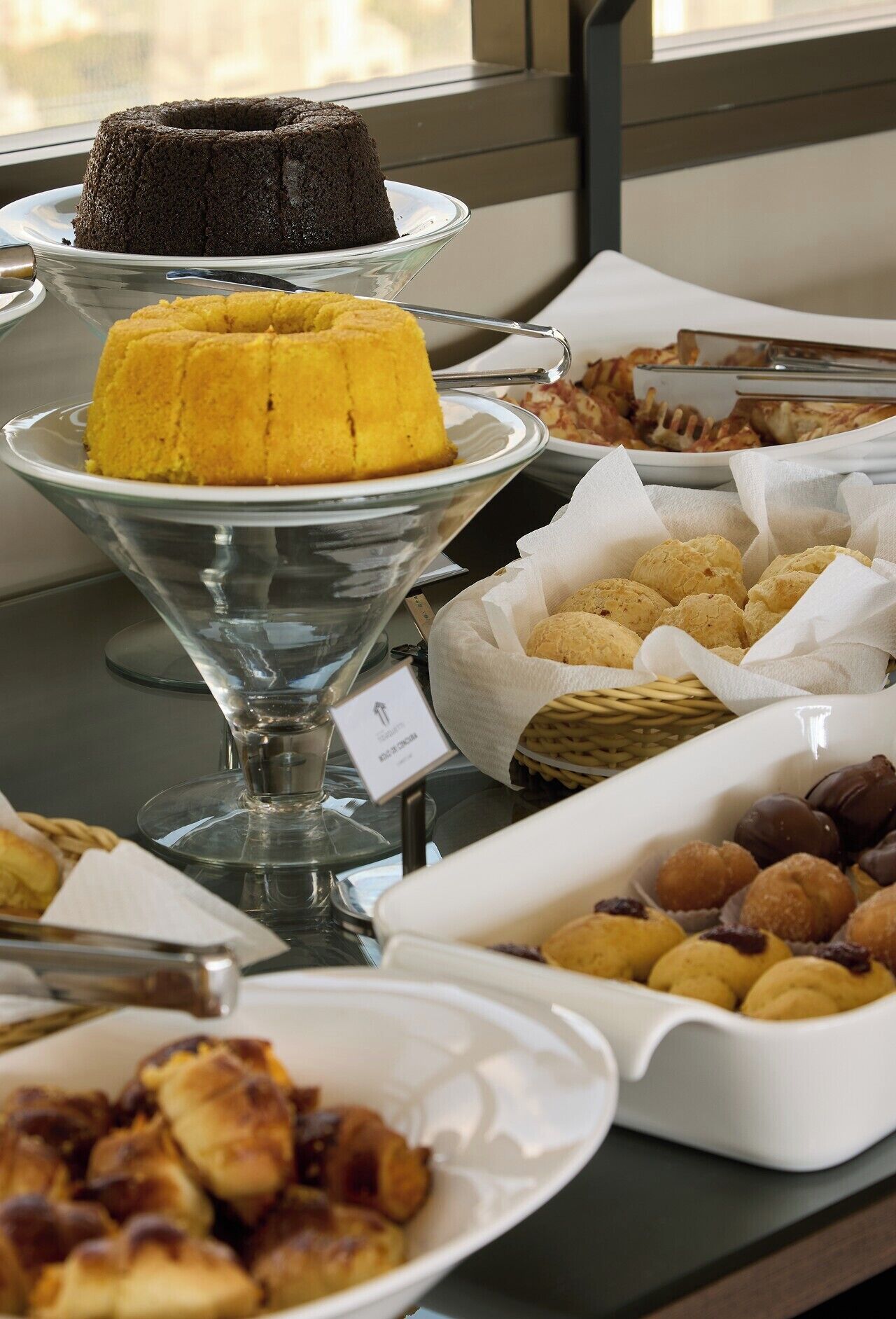A buffet table with various desserts including a bundt cake, a yellow cake, and assorted pastries.