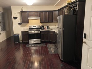 A kitchen with dark wooden cabinets, stainless steel appliances, and a red floor mat with "Kitchen" written on it. - Charming 2-bedroom Loft in superb Detroit with , WiFi (Detroit)
