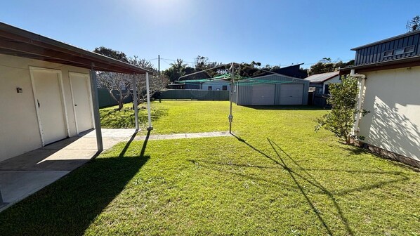 Un jardin avec une pelouse, un abri de jardin et un garage.