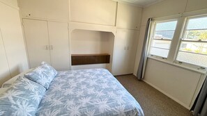 Une chambre à coucher avec un lit, une tête de lit, une fenêtre et une armoire.