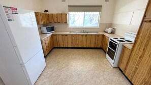 Une cuisine de taille réduite, dotée de meubles en bois, d’un four à micro-ondes, d’un évier, d’une cuisinière et d’un réfrigérateur.