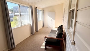 A room with large windows, a bench, and a wardrobe.