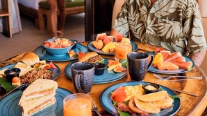 A dining table with various breakfast items, a bed, and a person walking in the background.