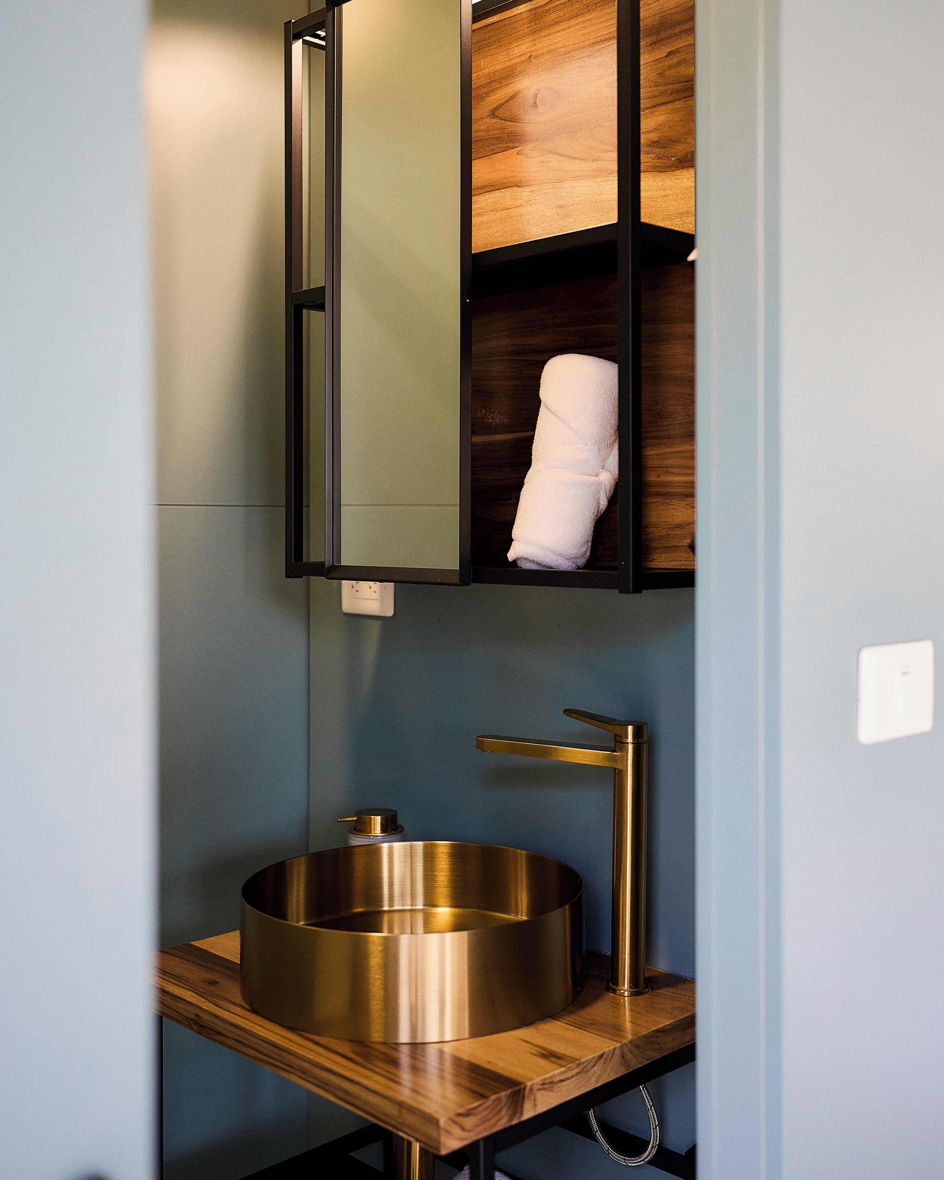 Un baño moderno con un lavabo redondo, un espejo y un perchero para toallas.