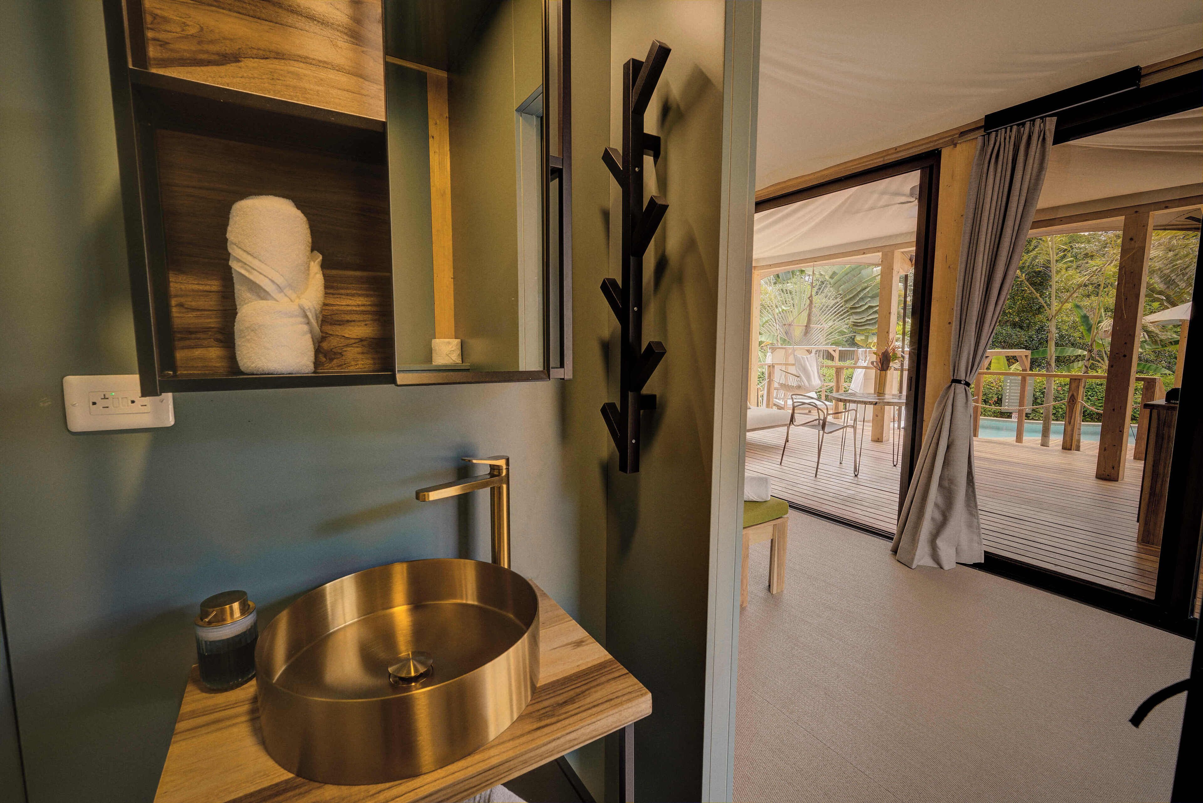 A bathroom with a wooden vanity, a large mirror, and a view of an outdoor deck with chairs and a table.