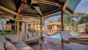 A wooden deck with a pool, a hammock, and a sofa.