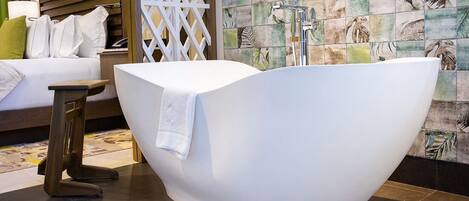 Une salle de bain moderne avec une baignoire sur pieds, un banc en bois et un mur recouvert de carreaux à motifs.