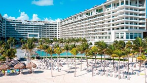 A hotel with multiple balconies, a pool area with lounge chairs, and palm trees. - Garza Blanca Resort and Spa (Punta Sam)