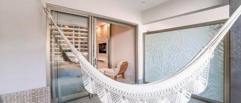 A hammock in a modern room with a glass door leading to a staircase.