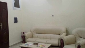 A living room with a sofa, armchairs, a coffee table, and a patterned rug. - Dar Bilel a beautiful place  (Tozeur)