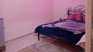 A bedroom with a bed, a wall-mounted artwork, and a ceiling light fixture. - Dar Bilel a beautiful place  (Tozeur)
