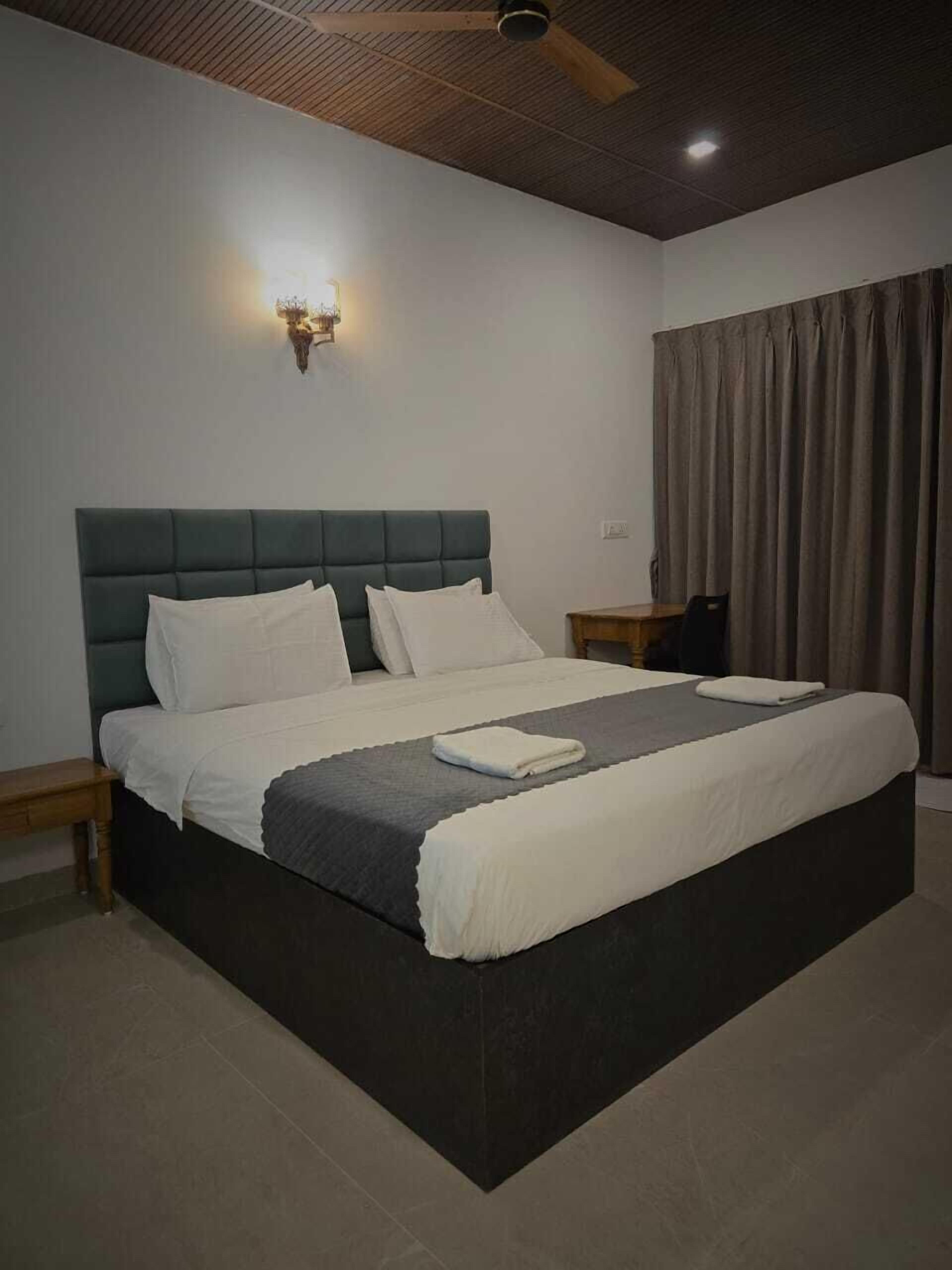 A modern bedroom with a large bed, a wooden headboard, a ceiling fan, and a nightstand.