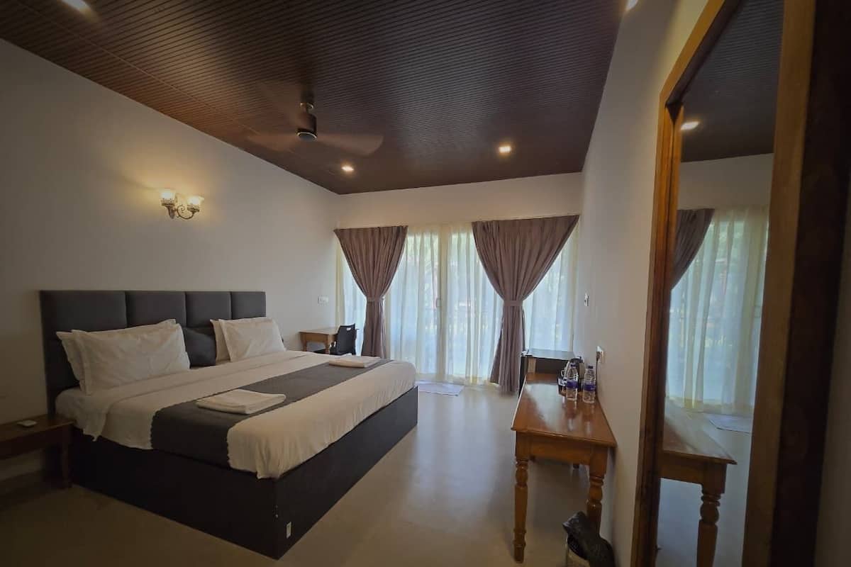 A bedroom with a large bed, a wooden table, and a ceiling fan.