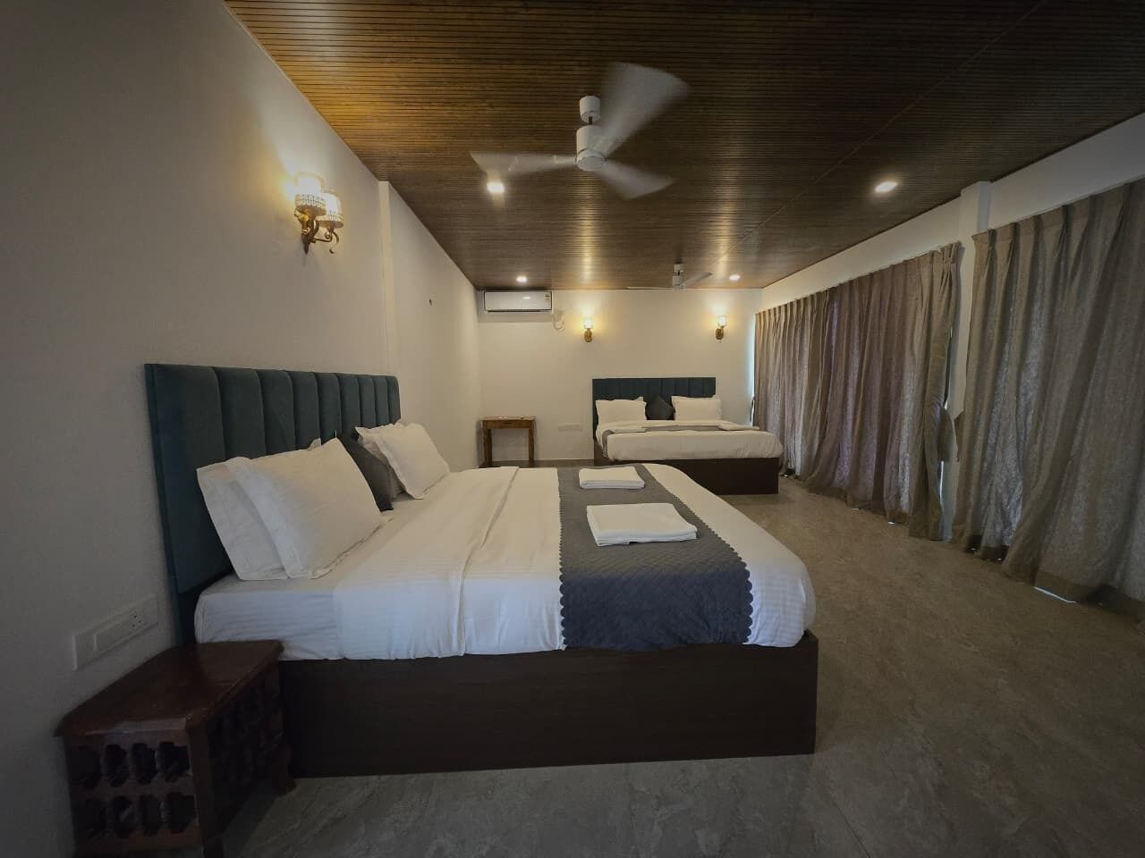 Une chambre avec un grand lit, un ventilateur de plafond et une fenêtre avec des rideaux.