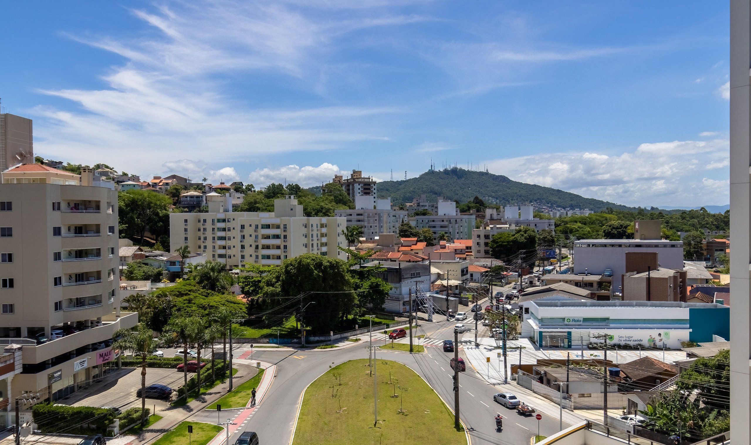 A cityscape with buildings, a road, and a hill in the background.
