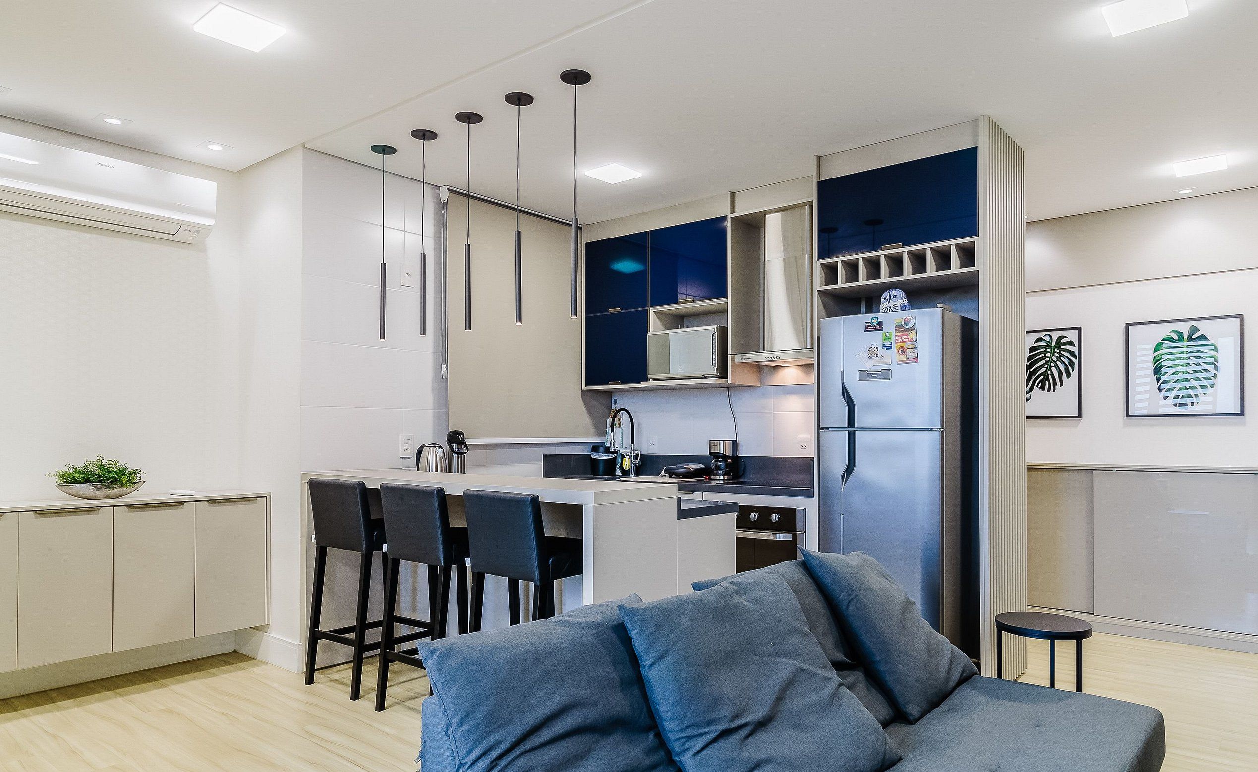 A modern kitchen with a central island, bar stools, a refrigerator, and a microwave.