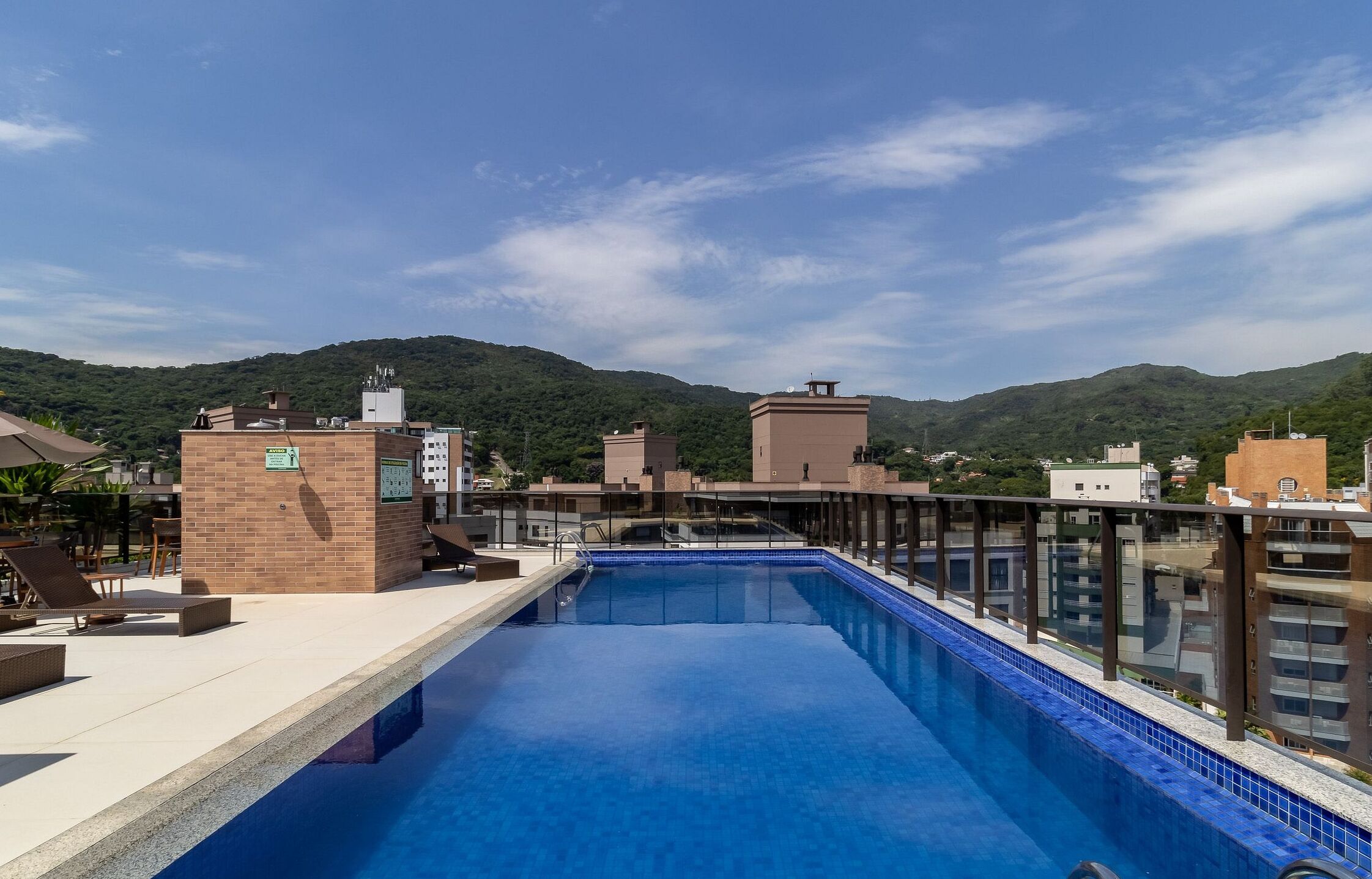 Una piscina en la azotea con vistas despejadas de los edificios circundantes y un paisaje montañoso.