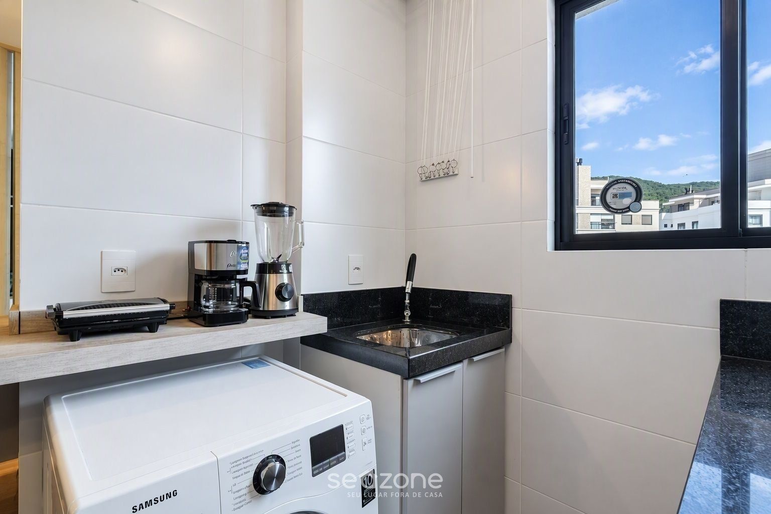A modern kitchen with a coffee maker, blender, and Samsung washing machine.