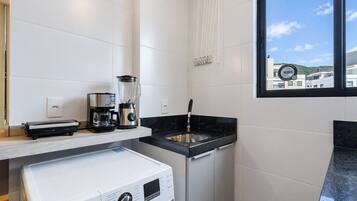 A modern kitchen with a coffee maker, blender, and Samsung washing machine.