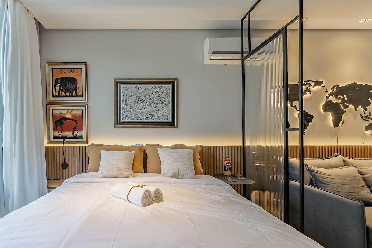 A hotel room with a large bed, a world map on the wall, and artwork depicting Zambia.