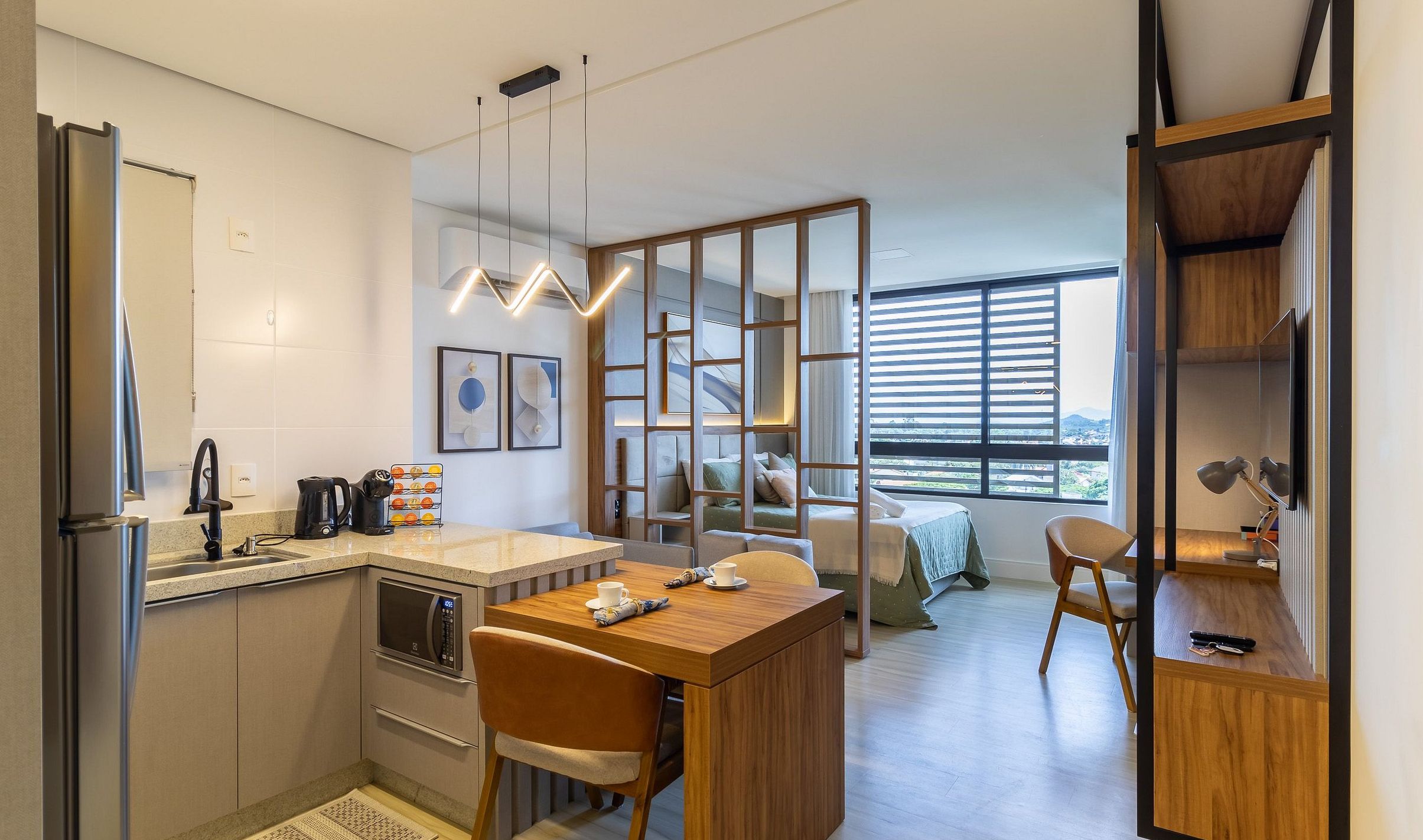 Een moderne keuken met een eethoek, een koffieapparaat en uitzicht op de stad door grote ramen.