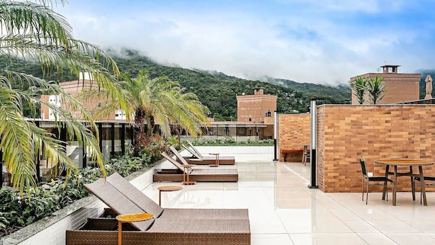 Une terrasse sur le toit, aménagée avec des chaises longues, une table à manger et offrant une vue sur un paysage montagneux.