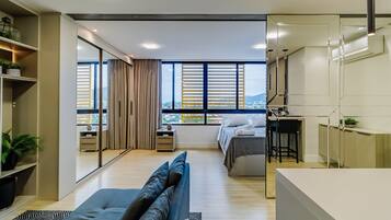 Habitación de hotel moderna con una cama grande, un sofá, un escritorio y vistas a la ciudad.