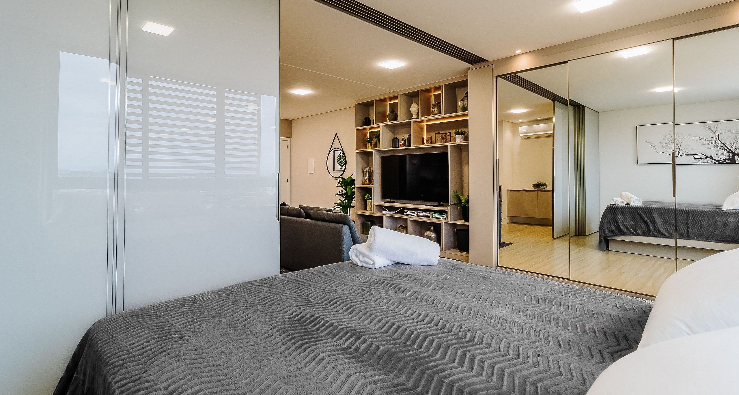 A modern bedroom with a large bed, a television, and a sliding door leading to a bathroom.