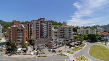 Un edificio de varios pisos con una planta baja comercial, rodeado por un parque arbolado y una glorieta.