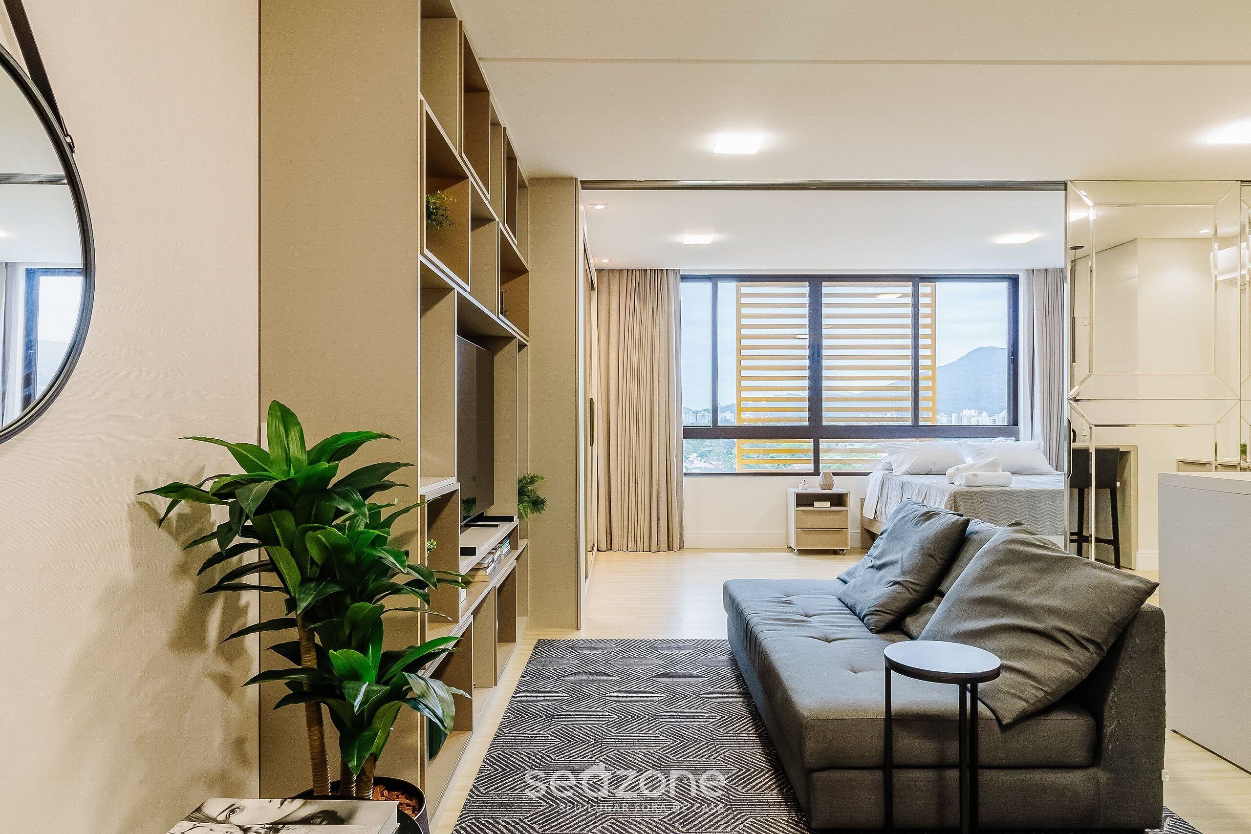 Una sala de estar moderna con un sofá, una mesita y un amplio ventanal con cortinas.