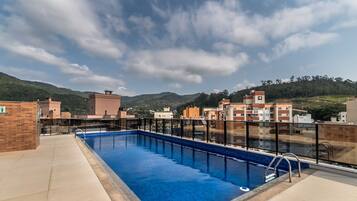 Una piscina en la azotea con vistas despejadas de edificios y colinas circundantes.