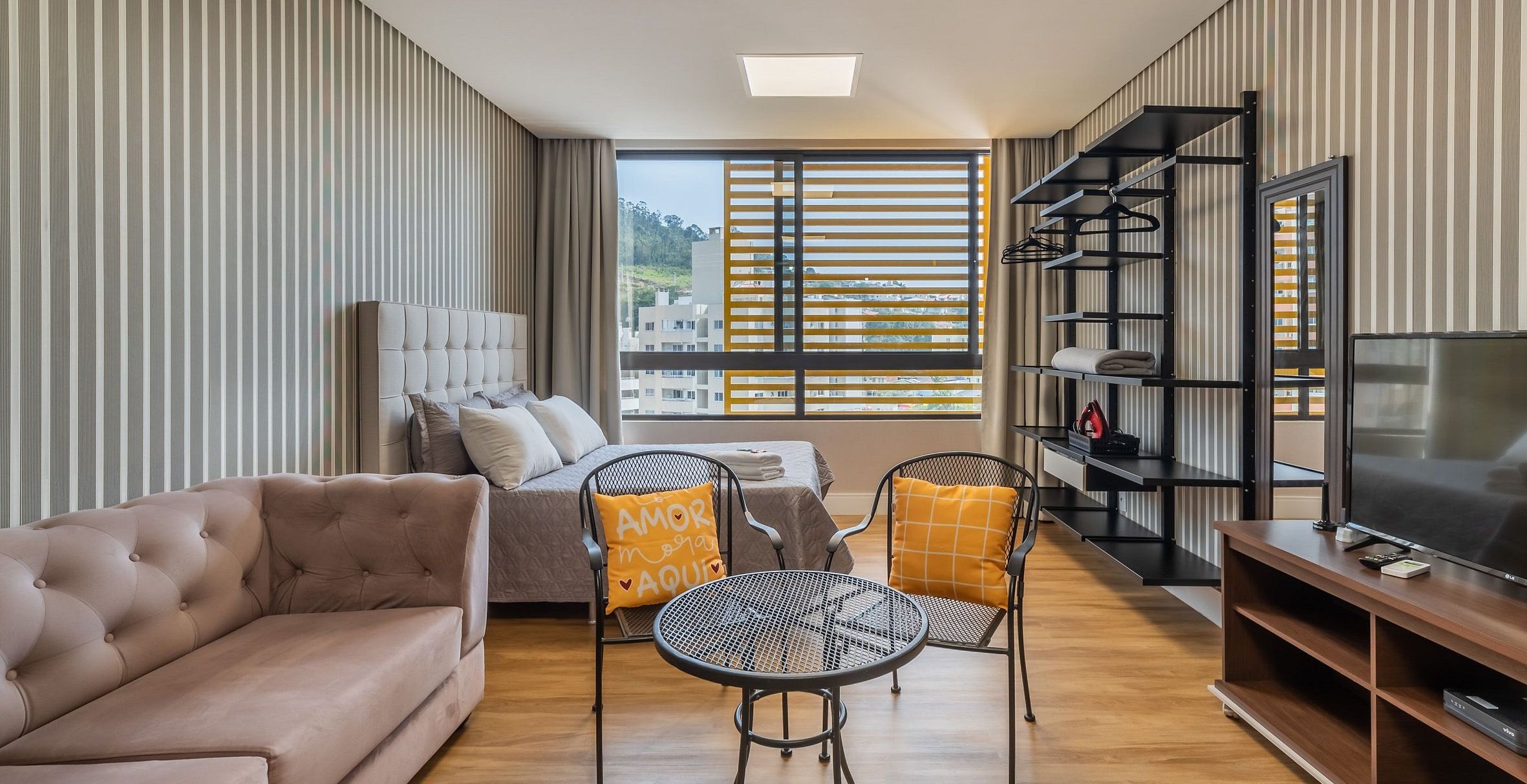 A modern living room with a sofa, a bed, a dining table, and a TV.