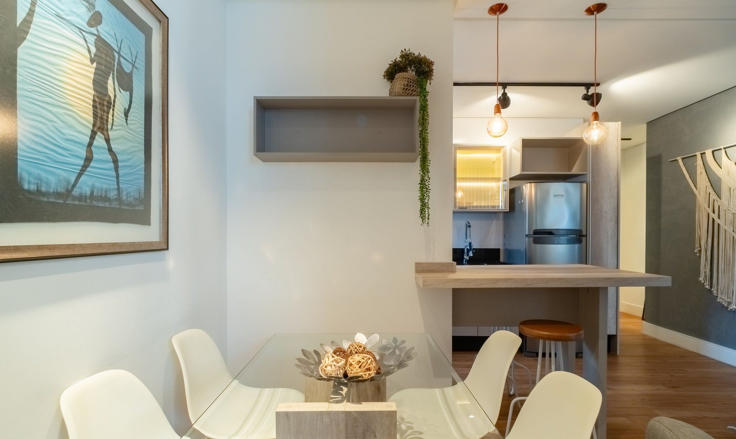 Una cocina moderna con un refrigerador empotrado, una planta colgante y un adorno de macramé en la pared.