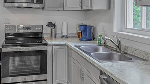 Une cuisine moderne dotée d’appareils électroménagers en acier inoxydable, de meubles de couleur grise et d’un plancher en bois.