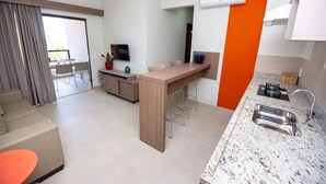 Een moderne hotelkamer met een keukenhoek, een eettafel en een zithoek.